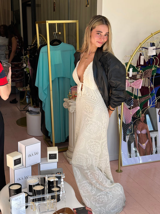 Woman standing beside a KĀ ÄS candle display at Tanaka Vintage pop-up shop in West Hollywood, wearing a white crochet dress and bomber jacket